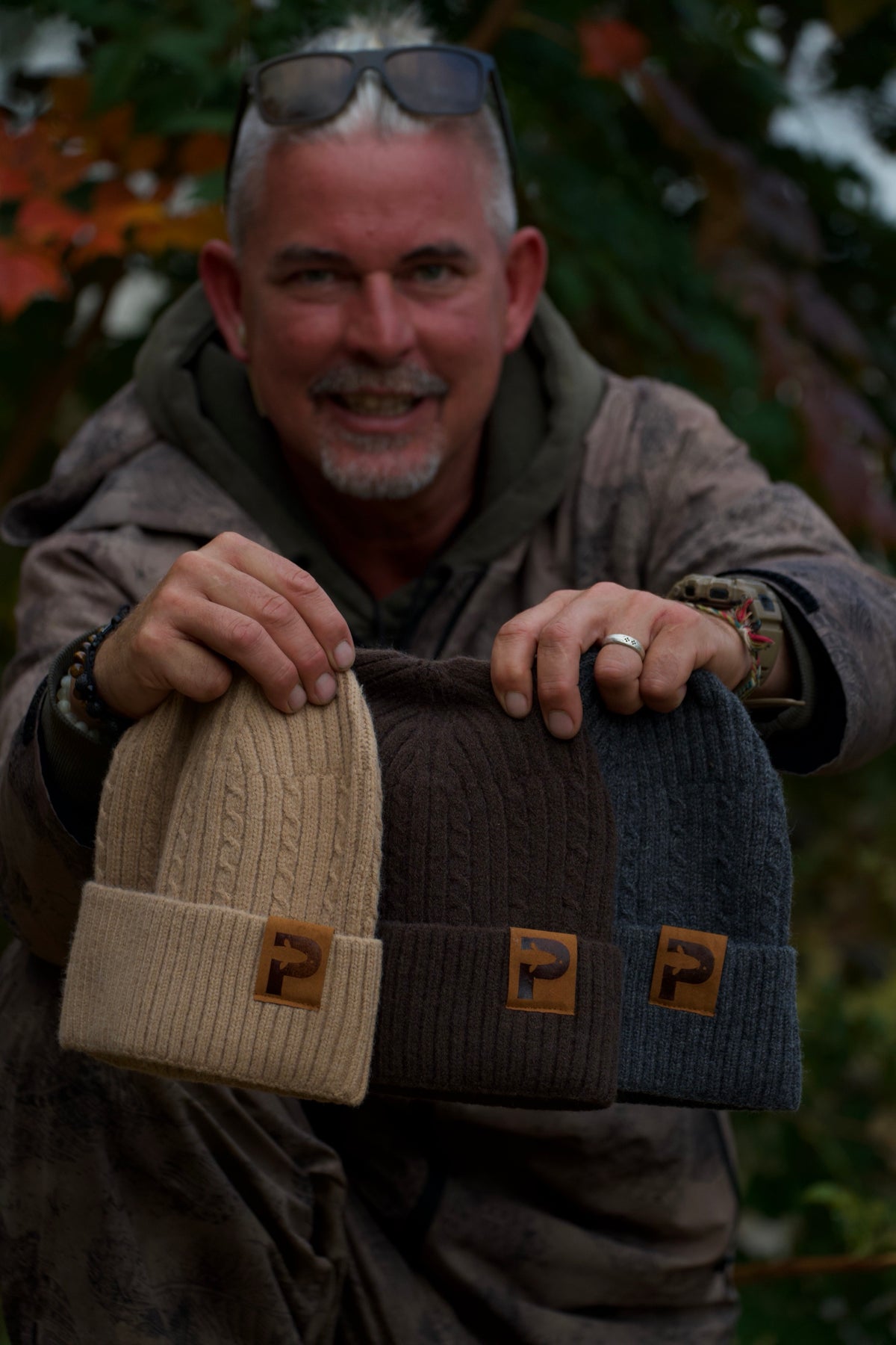 Angler hält die P Mütze in Beige, Braun und Grau in die Kamera